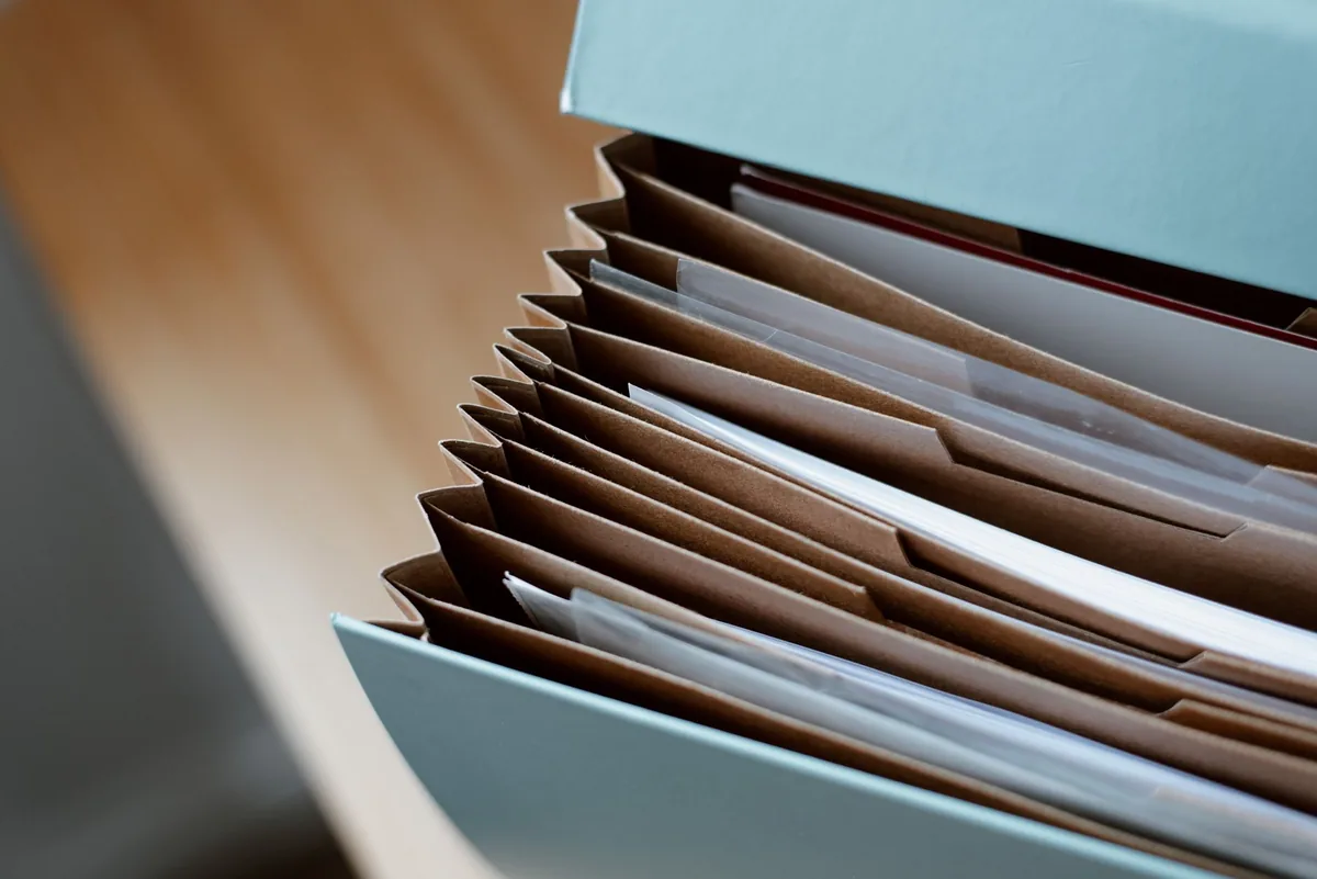 An accordion document folder packed with organized paperwork on a desk